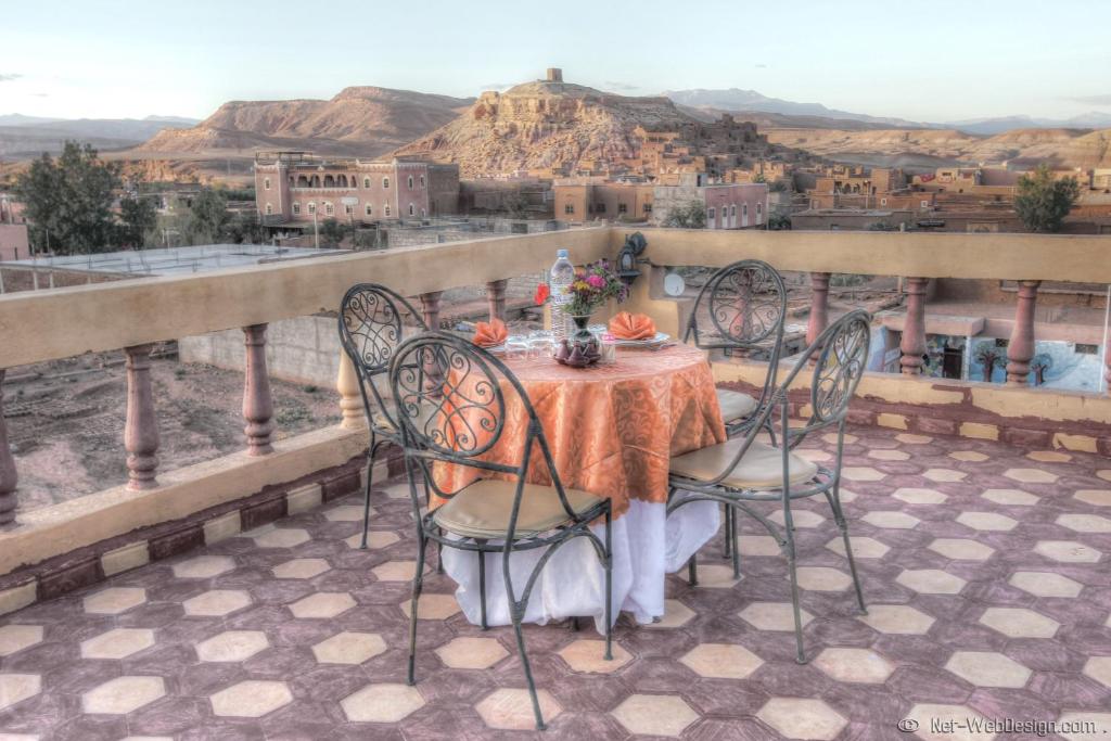 een tafel en stoelen op een balkon met uitzicht bij Kasbah Valentine in Aït Ben Haddou