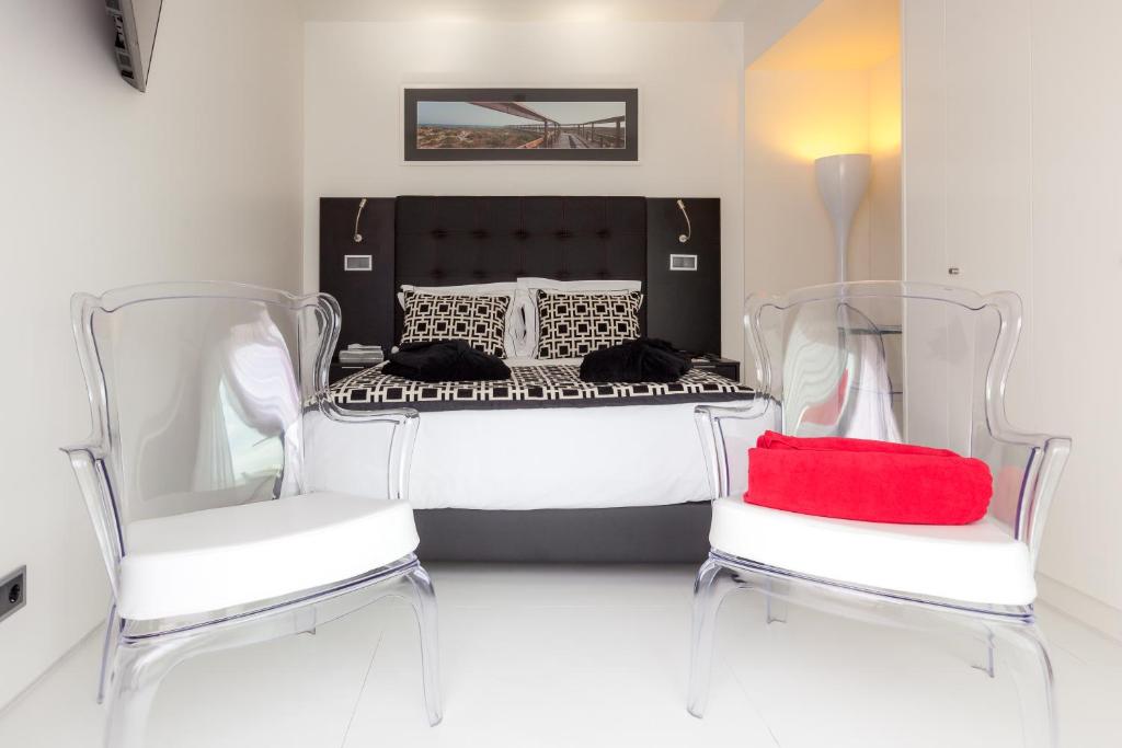 a bedroom with a bed and two chairs with a red pillow at Faro Boutique Hotel in Faro