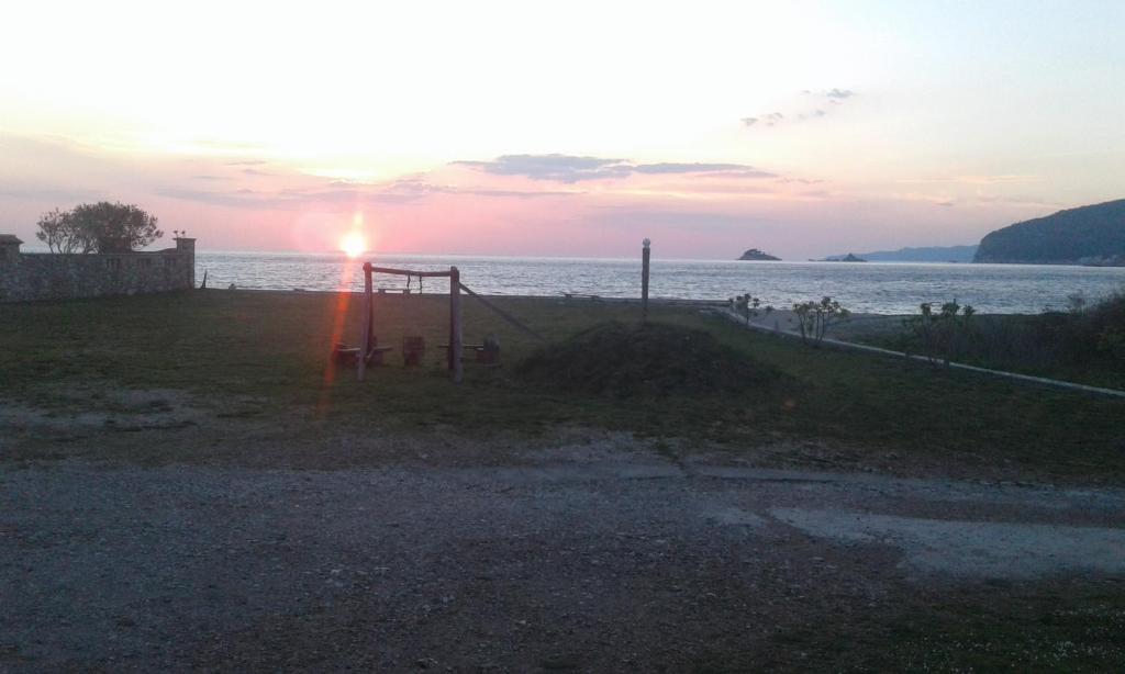 a sunset over a body of water with a fence at Buljarica Bay Apartments in Petrovac na Moru