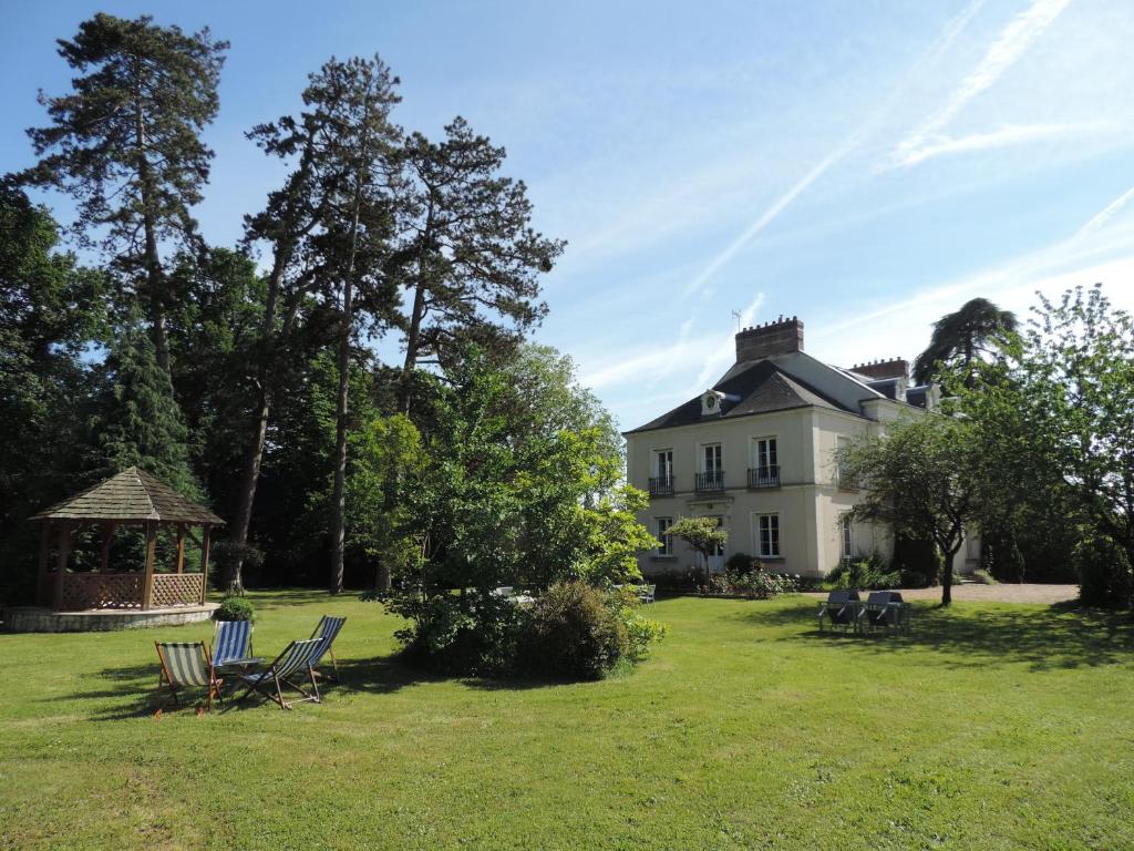 uma grande casa branca com cadeiras e um gazebo em Cèdre et Charme em Saint-Branchs