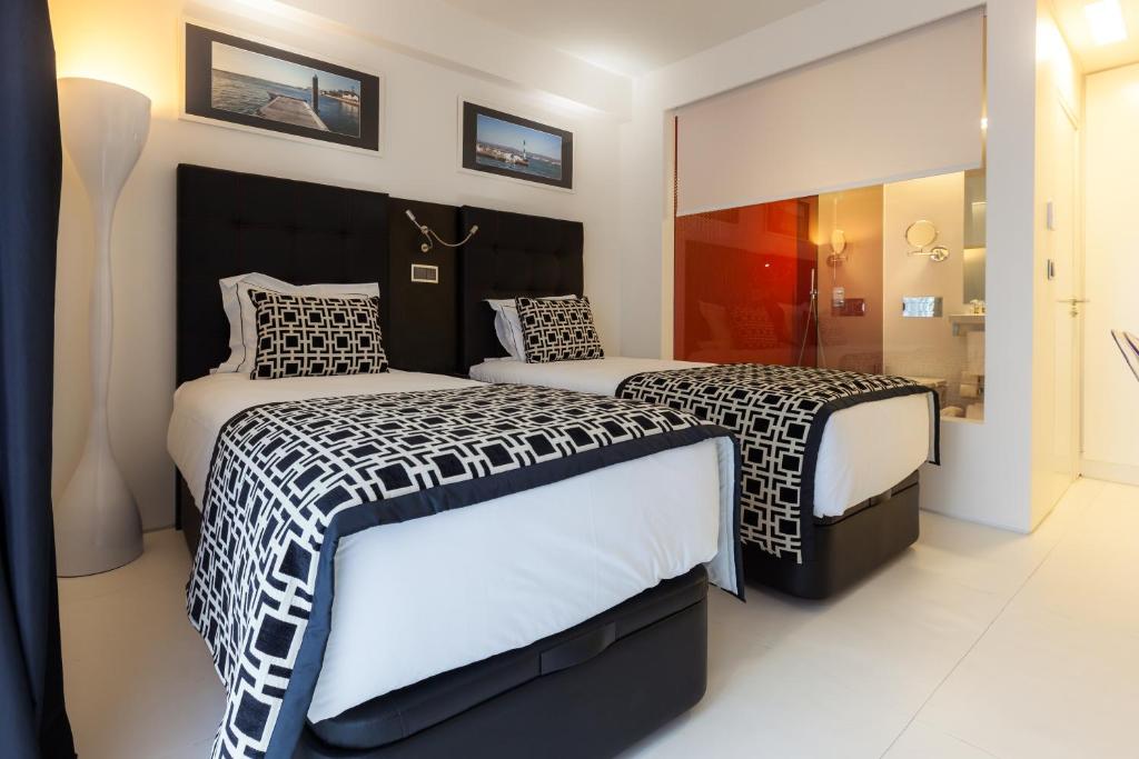 a bedroom with two beds with black and white sheets at Faro Boutique Hotel in Faro