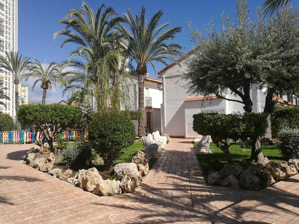 a garden with trees and rocks in front of a building at Rinconada Real Bungalows- Ap2000 in Benidorm