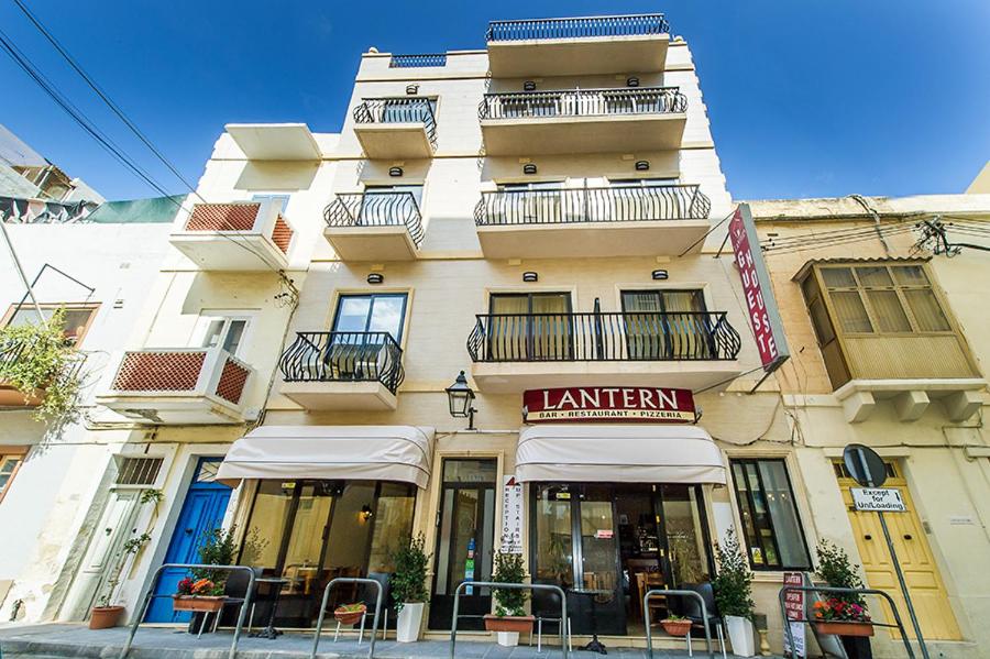 a tall building with a restaurant in front of it at Lantern Guest House in Marsalforn