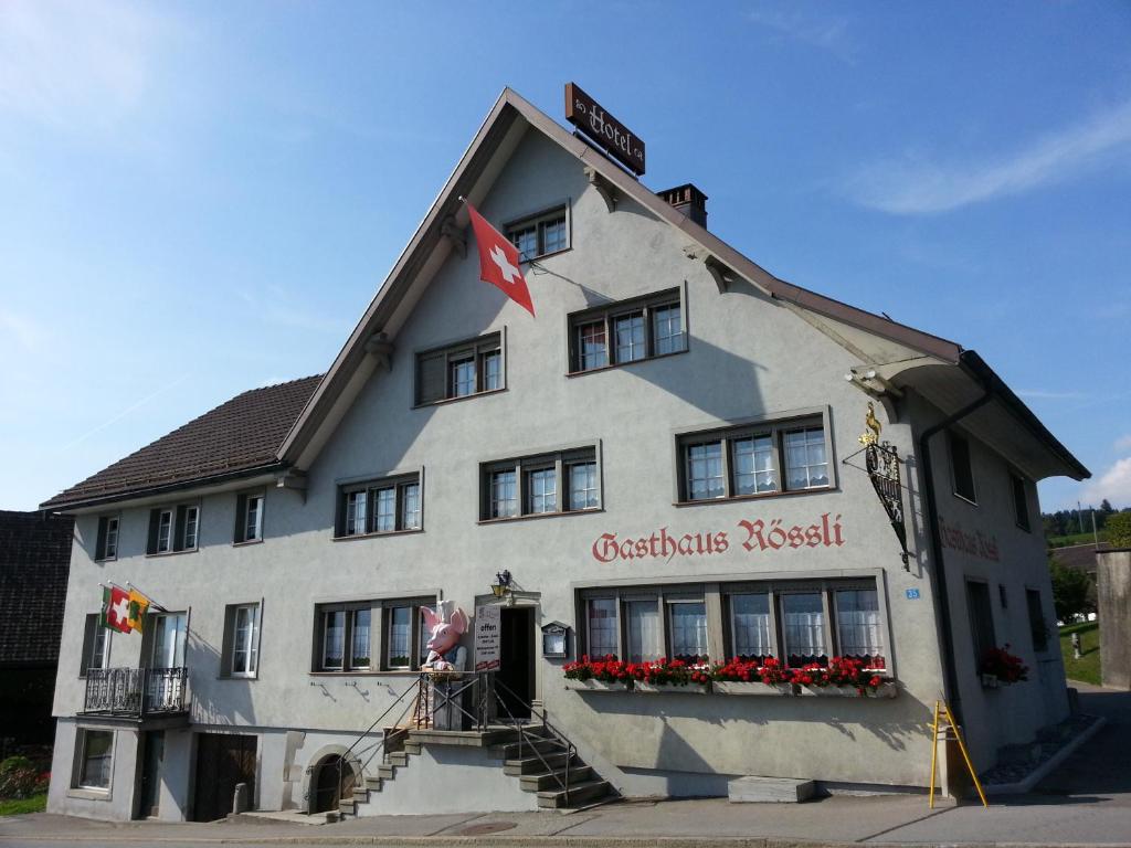 Ein großes weißes Gebäude mit einer roten Flagge. in der Unterkunft Gasthaus Rossli in Sankt Gallenkappel