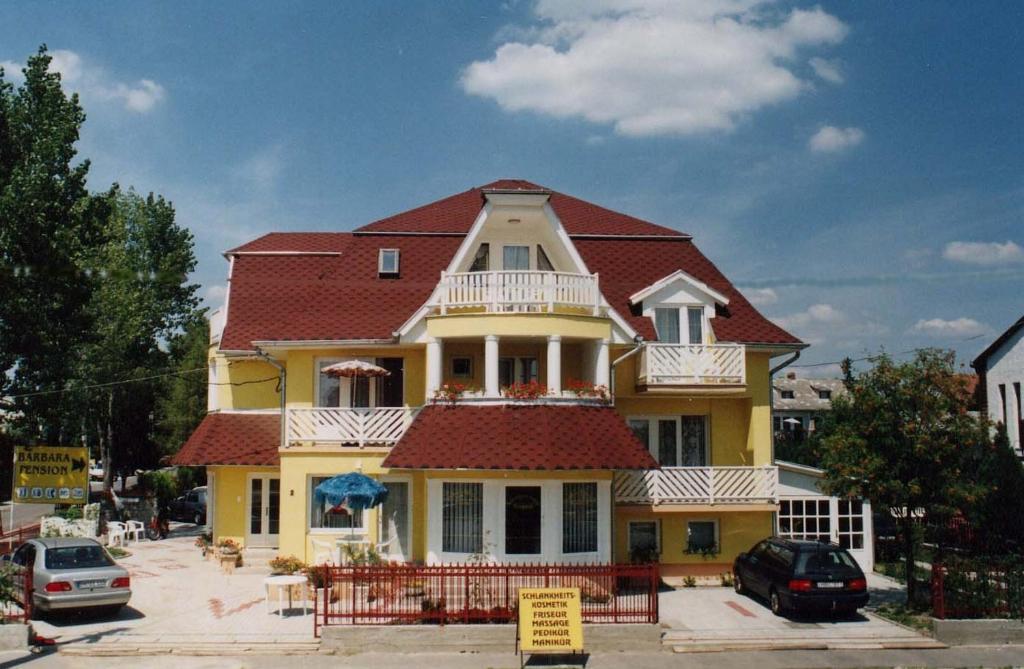 a large yellow house with a red roof at Barbara Wellness Pension in Keszthely