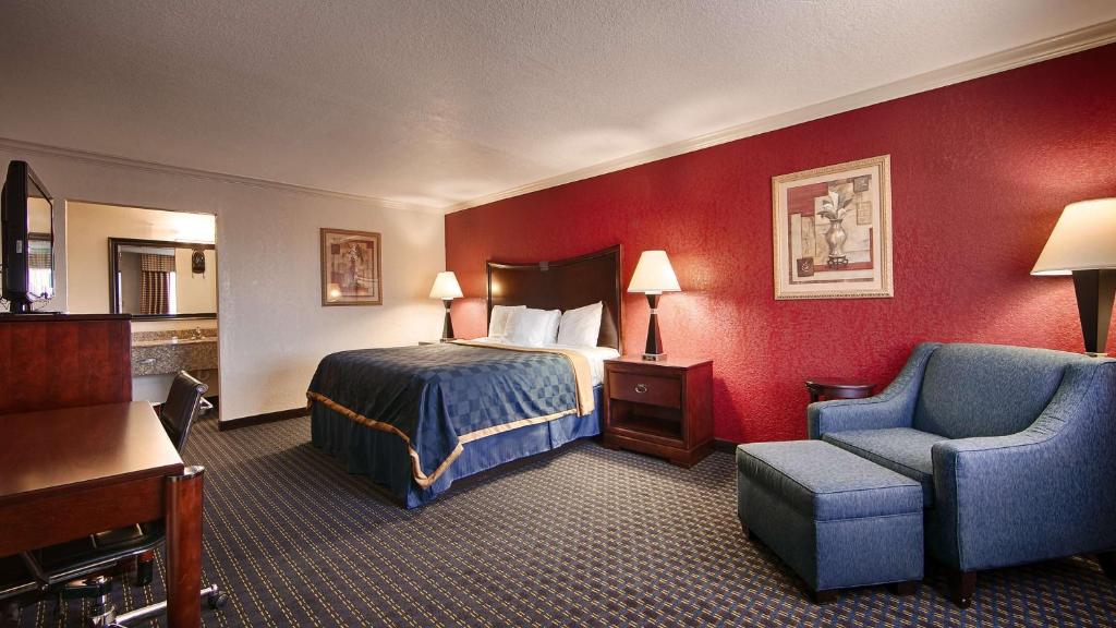 Habitación de hotel con cama y silla en Americas Best Value Inn Kingsville, en Kingsville