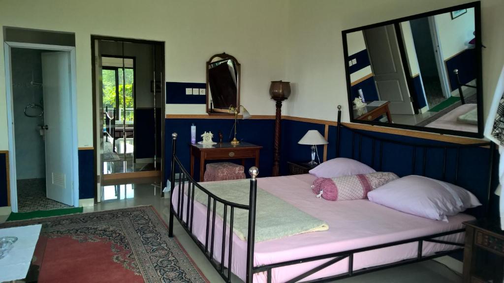 a bedroom with a bed with pink sheets and mirrors at Villa Bella in Batu