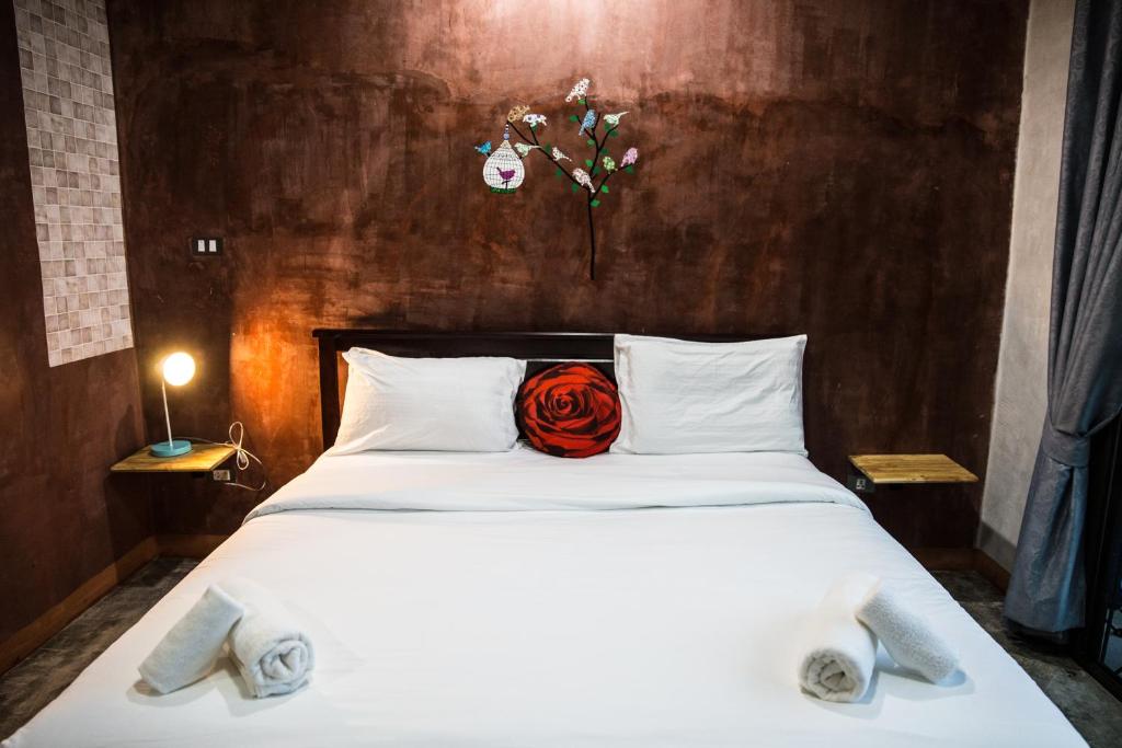 ein Schlafzimmer mit einem weißen Bett mit einer roten Rose darauf in der Unterkunft The Boat House in Ranong