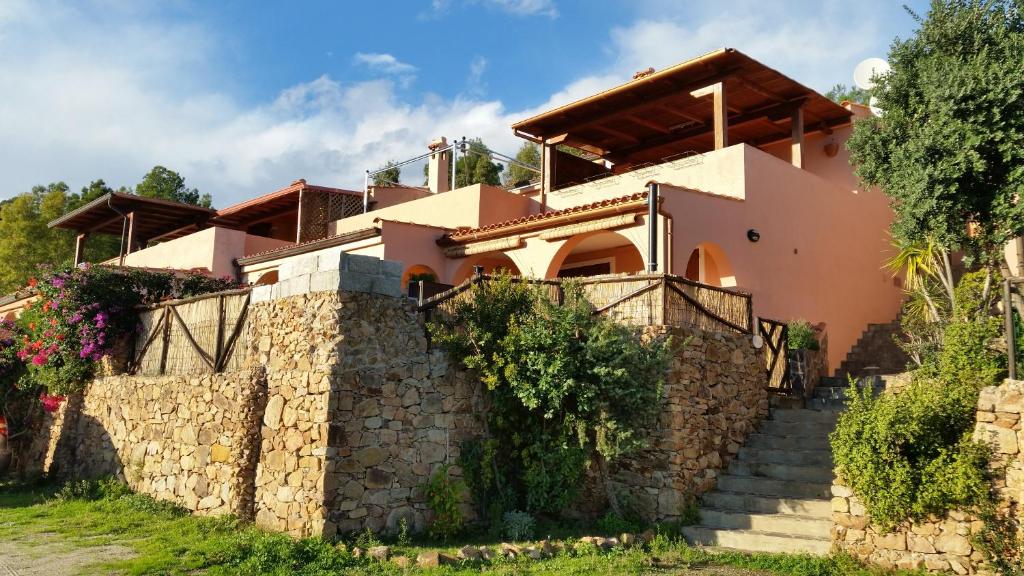 una casa con un muro in pietra e scale di Villa Eden IUN Q0499 a Santa Margherita di Pula