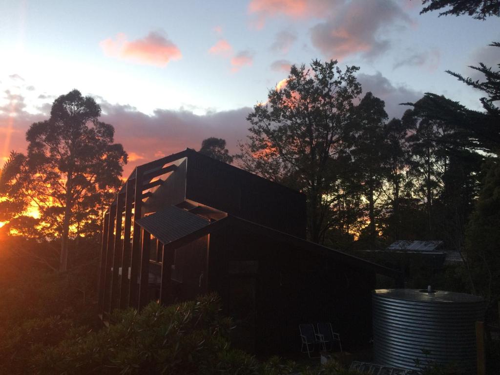 a house with the sunset in the background at Pipeline Chalet kunanyi Mt Wellington in Ferntree