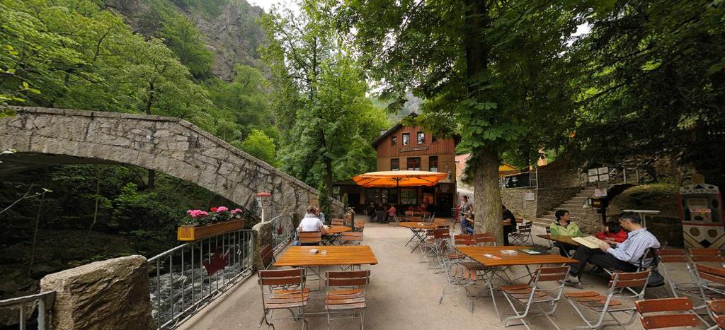 eine Gruppe von Menschen, die an Tischen in der Nähe einer Brücke sitzen in der Unterkunft Gasthaus Koenigsruhe in Thale