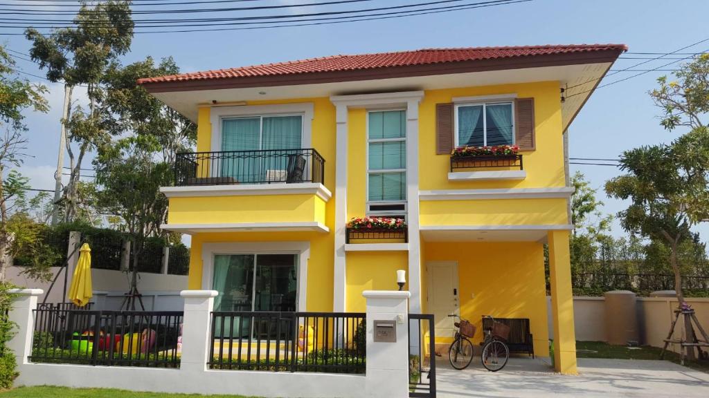 une maison jaune avec 2 balcons et un vélo dans l'établissement Tascany Sea Beach Chaam-Huahin, à Cha Am
