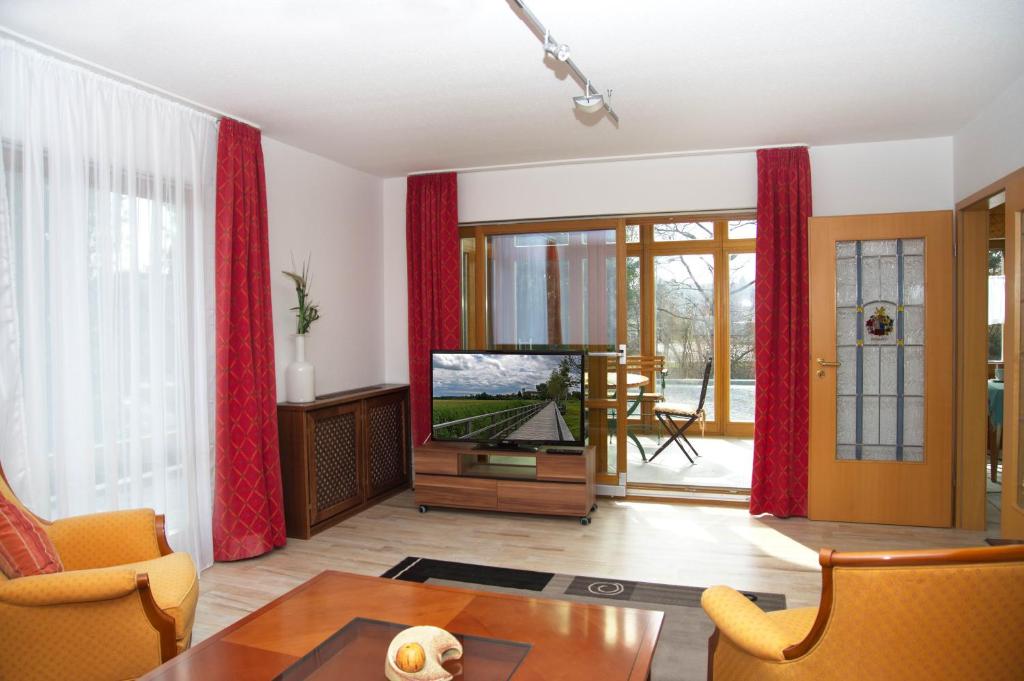 uma sala de estar com televisão e cortinas vermelhas em Ferienhaus Bauerngarten em Bad Buchau