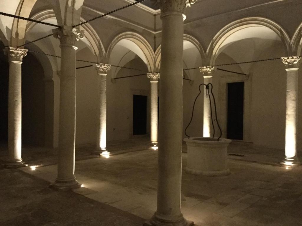 una stanza vuota con colonne e campanelli in un edificio di The Sound of Silence a L'Aquila