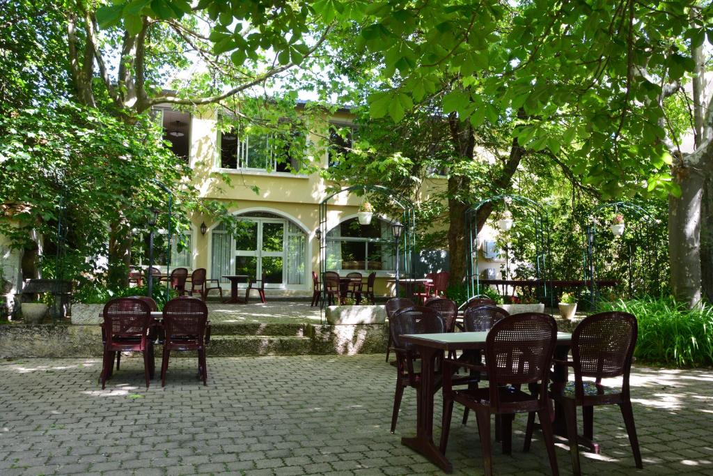 un patio avec des tables et des chaises sous un arbre dans l'établissement Logis Le Ceans, à Orpierre