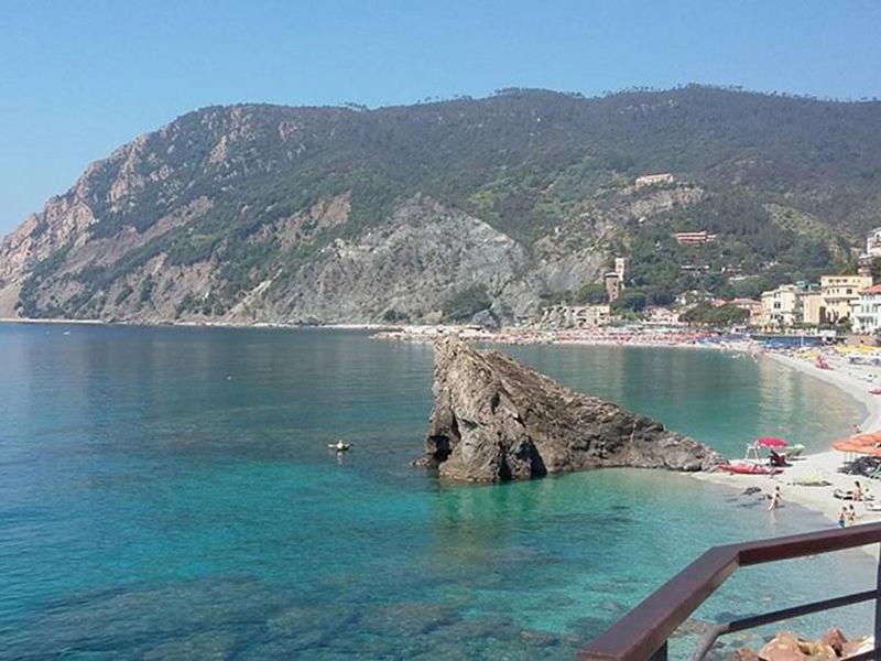 a beach with a large rock in the water at Casa Manu Apartments in Monterosso al Mare