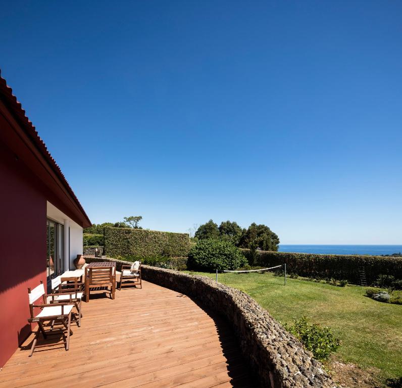 Quinta da Tilia Boutique Retreat في كابيلاس: سطح خشبي مع مقاعد والمحيط في الخلفية