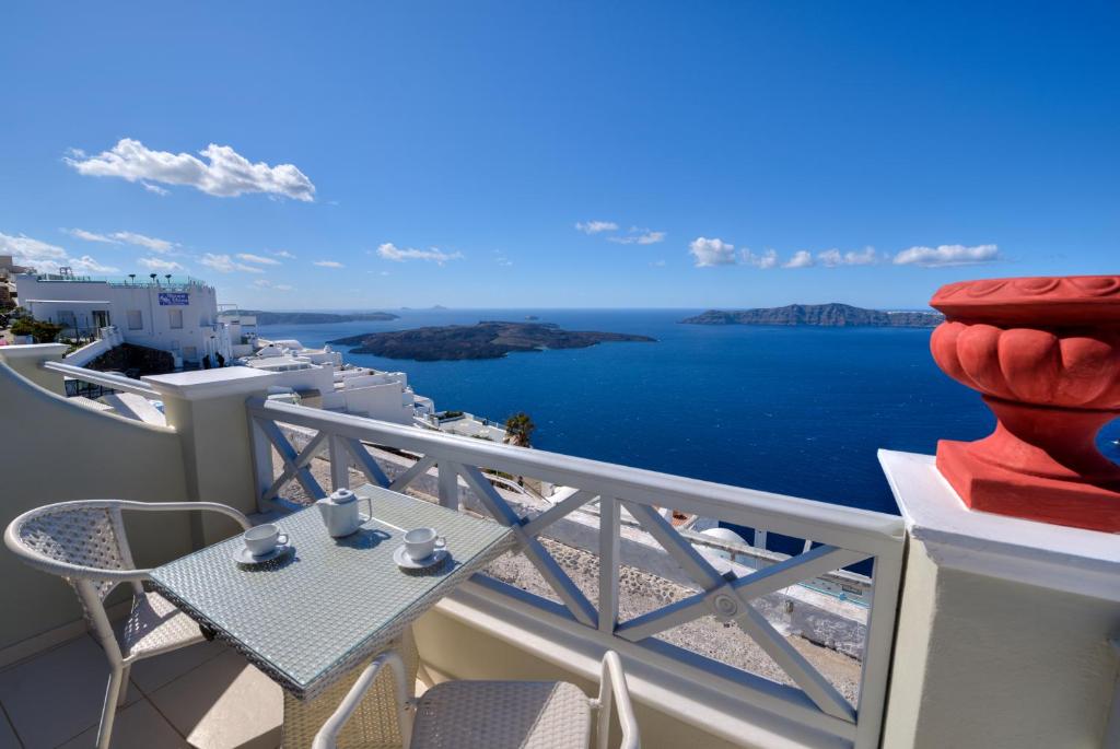 een balkon met een tafel en uitzicht op de oceaan bij Ellinon Thea Boutique Hotel in Firostefani