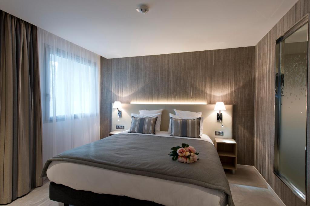 a bedroom with a large bed with flowers on it at Golden Tulip Sophia Antipolis - Hotel &amp; Spa in Valbonne