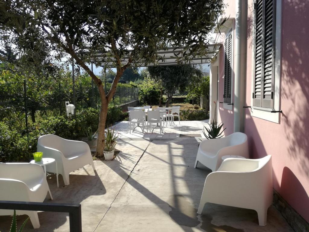 eine Terrasse mit weißen Stühlen, Tischen und einem Baum in der Unterkunft Miss Sicily B&B in Terrasini