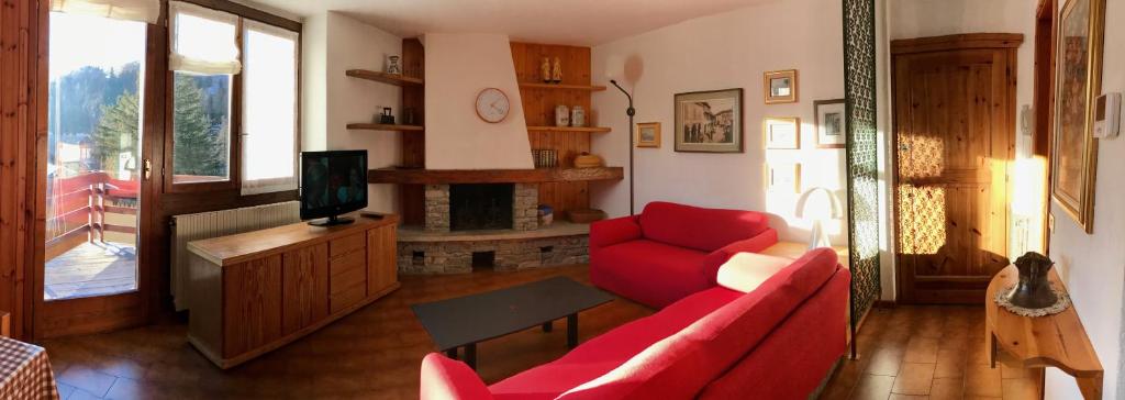 a living room with a red couch and a tv at CinqueSensi - Condominio La Zoca in Madesimo