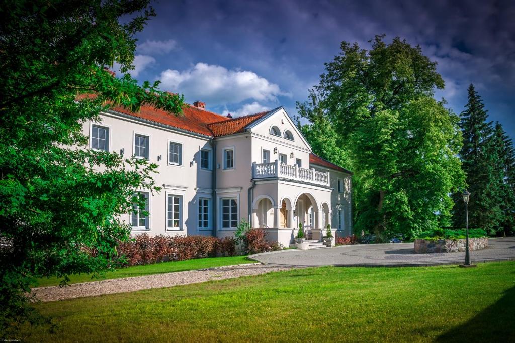 ein großes weißes Haus mit einem großen Hof in der Unterkunft Dwór Kaliszki in Kaliszki