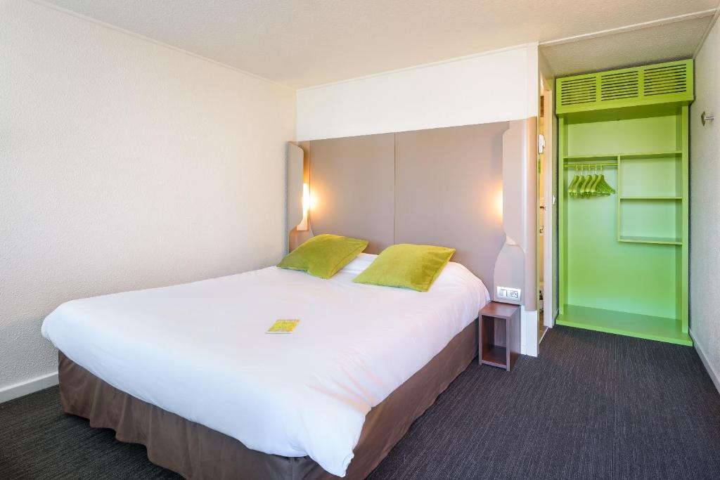 a bedroom with a large white bed with green accents at Campanile Toulouse Sesquieres in Toulouse