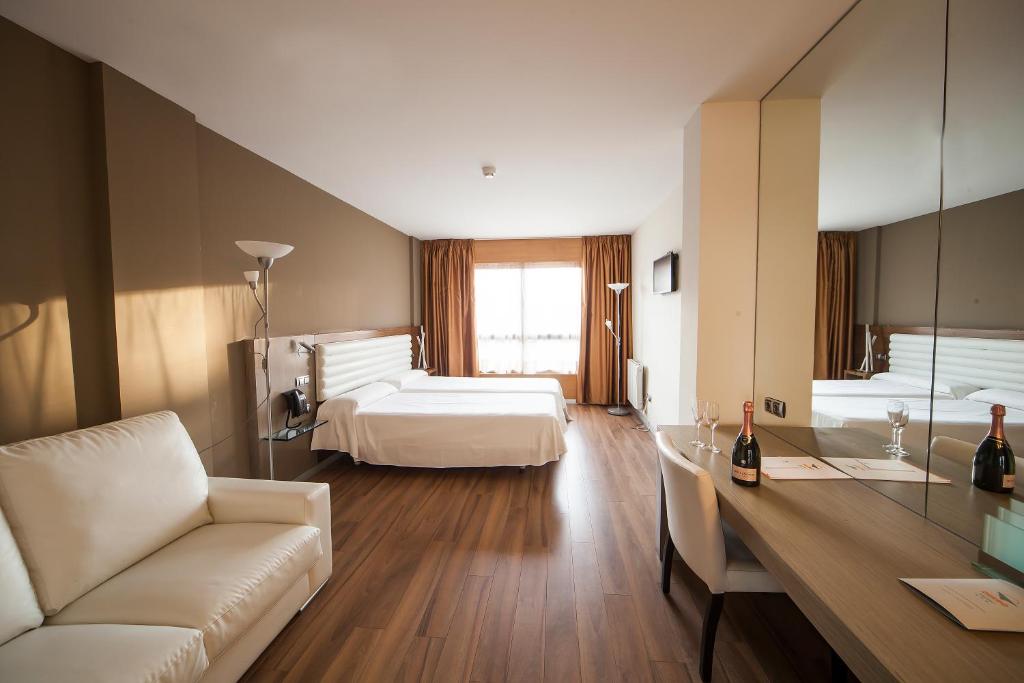 a hotel room with two beds and a desk at Hotel Duero in Laguna de Duero