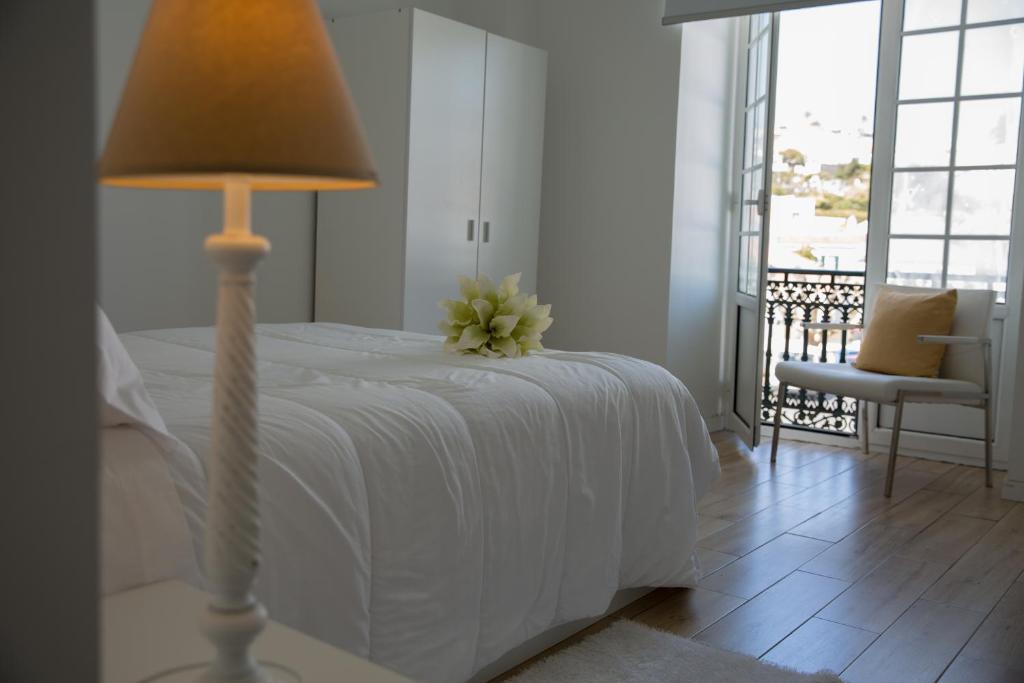 オルタにあるAzores Horta Apartments T0のベッドルーム(白いベッド、ランプ、椅子付)