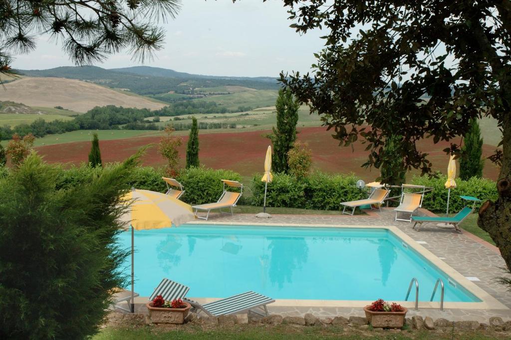 una piscina en un jardín con sillas y sombrilla en Agriturismo Palazzo Conti - B, en Pienza