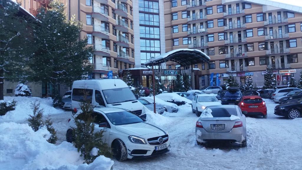 een met sneeuw bedekte straat met auto's geparkeerd voor gebouwen bij Studio in Hotel Flora Borovets in Borovets