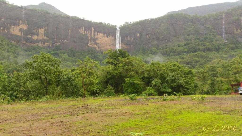 a waterfall in the middle of a field next to a mountain at Jamrung Hillside Camping in Jambrung 