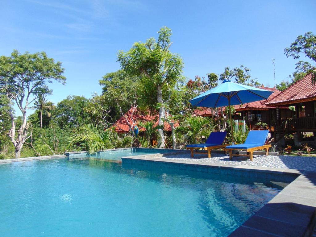 a swimming pool with two chairs and an umbrella at Starfish Lembongan in Nusa Lembongan