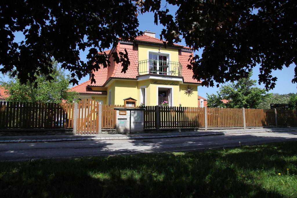 チェスキー・クルムロフにあるスルネスニ ドマの門と柵のある黄色い家