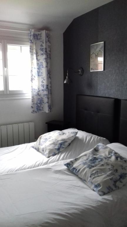 a bedroom with a bed with white sheets and a window at Logis Hôtel-Restaurant Les Airelles in Neufchâtel-en-Bray