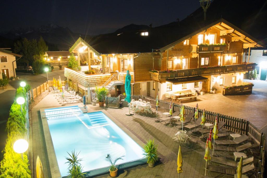 una vista aérea de una casa con piscina por la noche en Bodenhof Ferienwohnungen, en Fieberbrunn