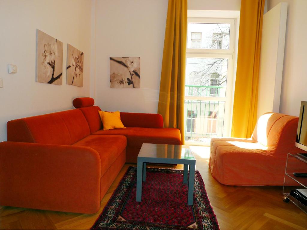 ウィーンにあるCity Apartments Wien - Viennapartmentのリビングルーム(オレンジ色のソファ、テーブル付)