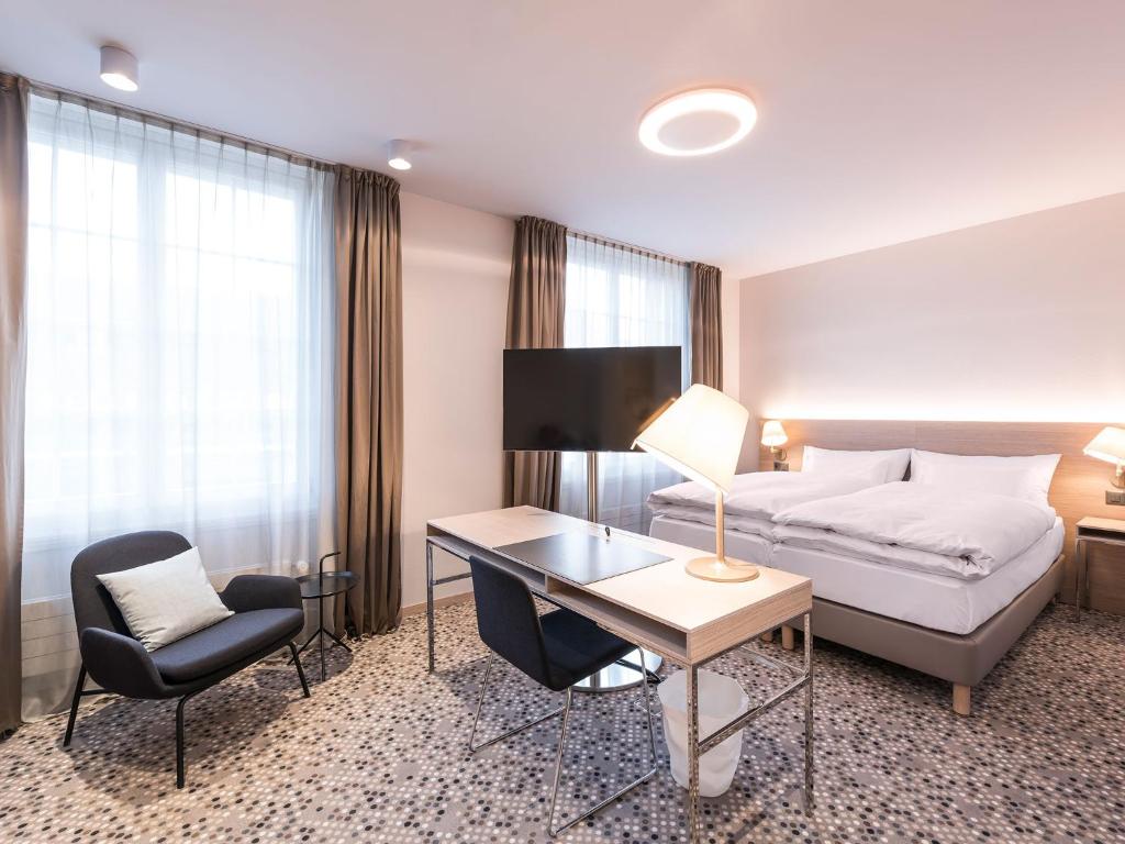Habitación de hotel con cama, escritorio y silla en Hotel Savoy, en Berna