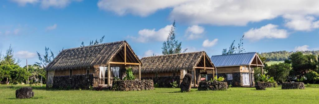 a house in a field with hay bales in front of it at Pacific Bungalows in Hanga Roa