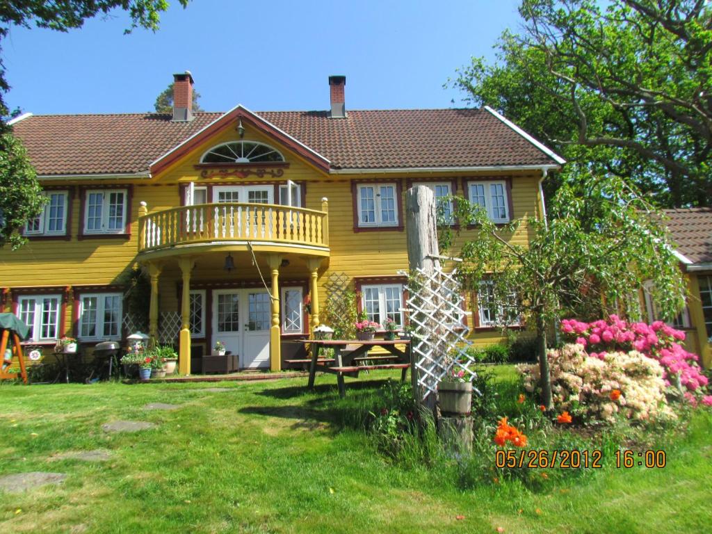 a yellow house with a deck on a yard at Bondegårdsparken Farm Holiday in Kristiansand