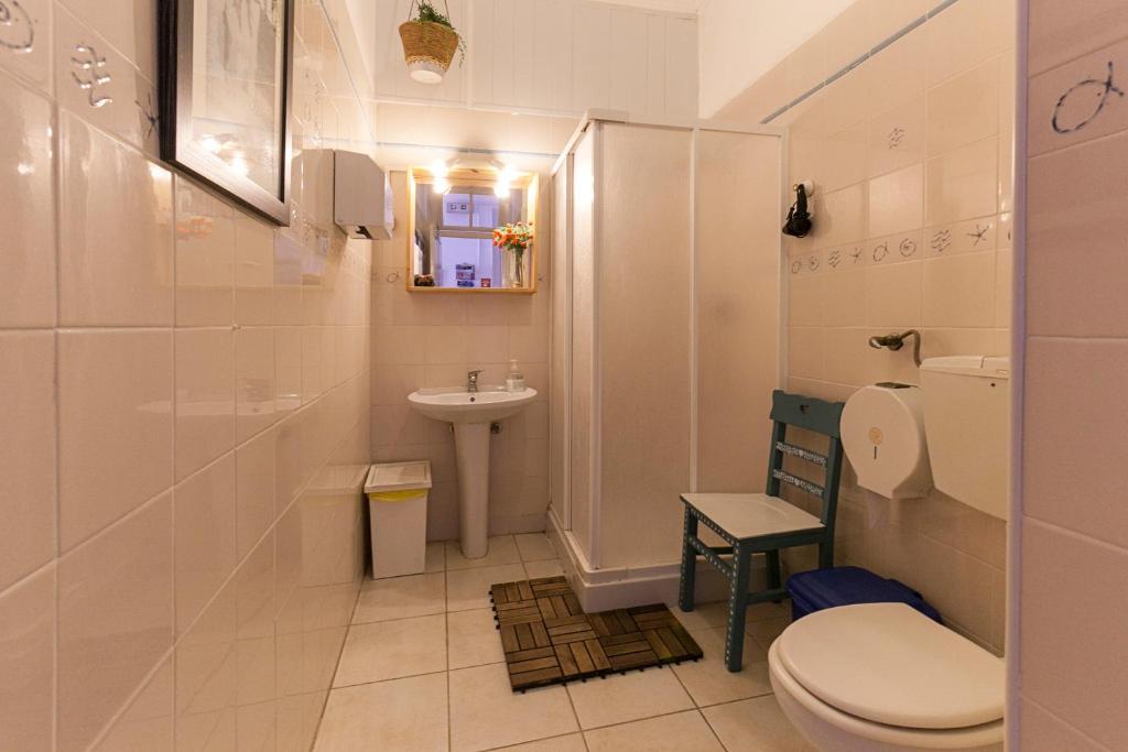 a white bathroom with a toilet and a sink at Peniche Hostel in Peniche