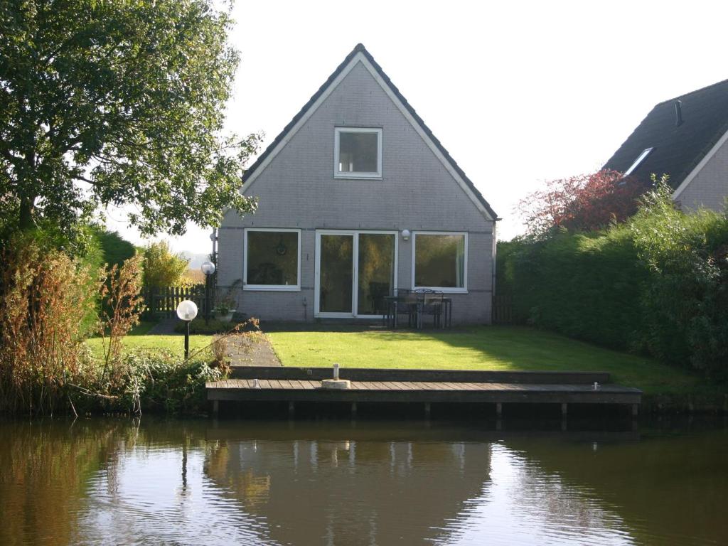 una casa con un muelle junto a un cuerpo de agua en Comfy bungalow with a dishwasher, at the water en Medemblik