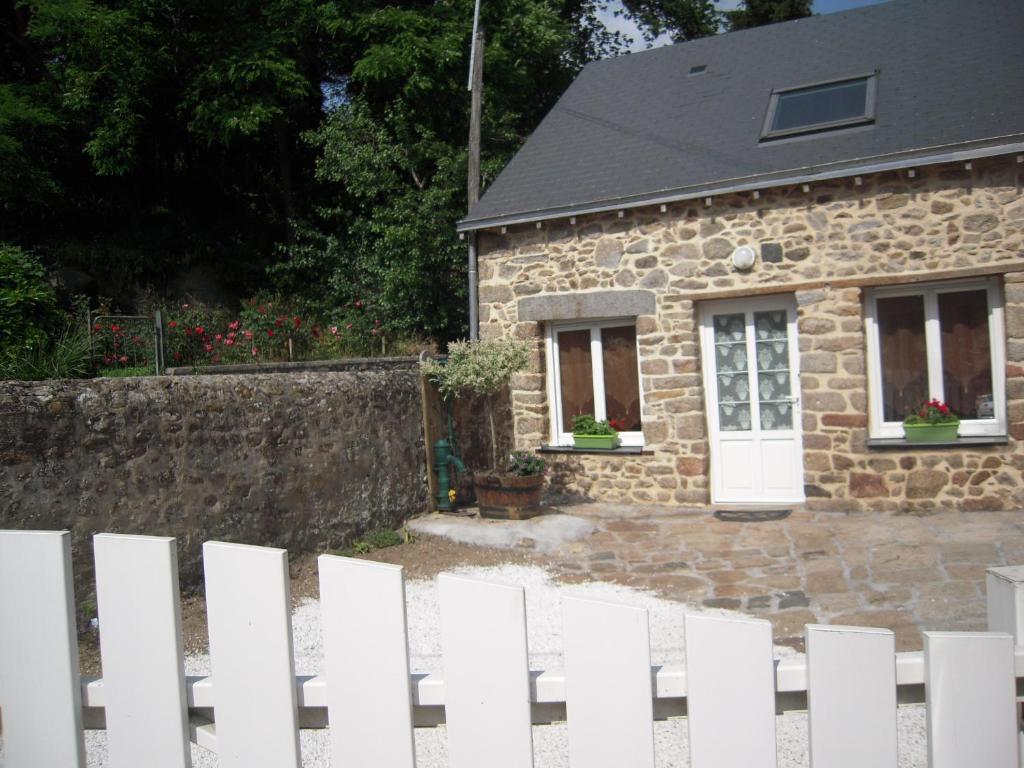 une clôture blanche en face d'une maison en pierre dans l'établissement Gite La Forge, à Alexain