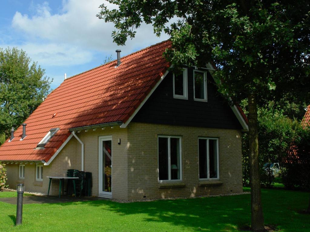 una casa con techo naranja en un patio en Restful Apartment with Garden, Private Terrace,Swimming Pool, en Westerbork