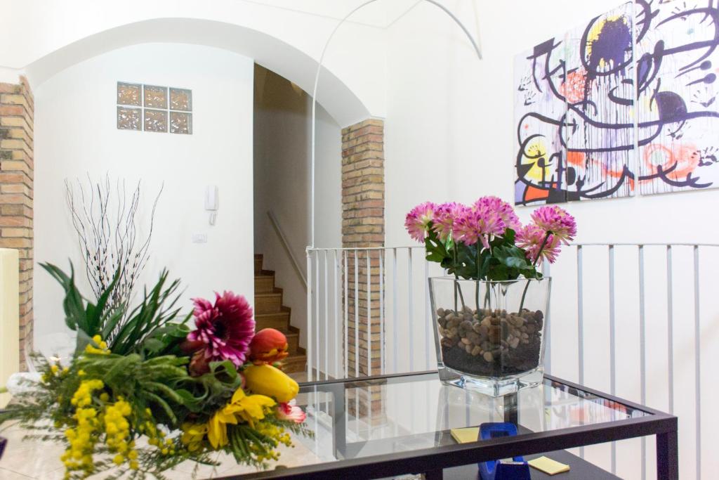 una habitación con una mesa de cristal con flores. en Le Stanze Dell'Imperatore B&B, en Melfi