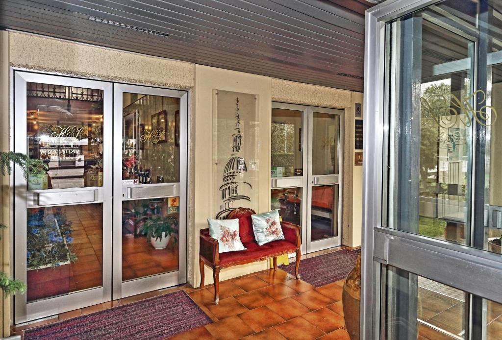ノヴァーラにあるHotel Residence Sognoの赤い椅子とガラス戸付きのポーチ