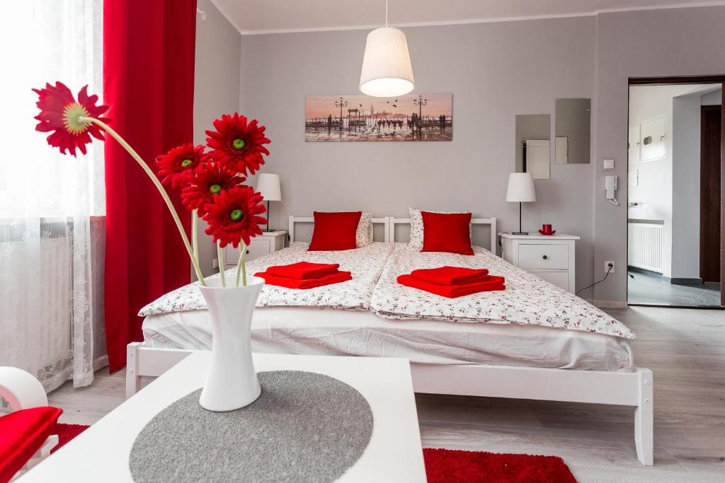 a bedroom with a bed with red pillows and a vase with flowers at Grey House in Wrocław