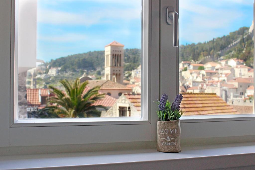 uma janela com um vaso com flores no parapeito da janela em Hortenzia Apartments em Hvar