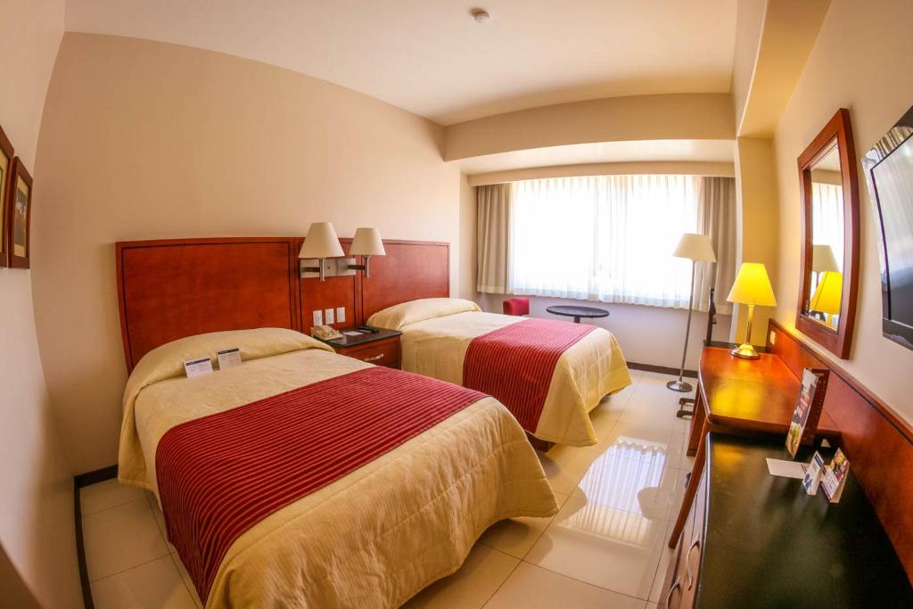 a hotel room with two beds and a window at Hotel Fortin Plaza in Oaxaca City