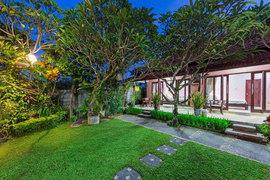 un jardín de una casa con árboles y césped en Wayan's Guesthouse, en Canggu